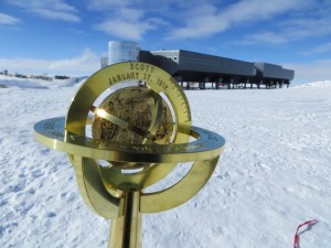 South Pole Marker, with the South Pole Station in the background.